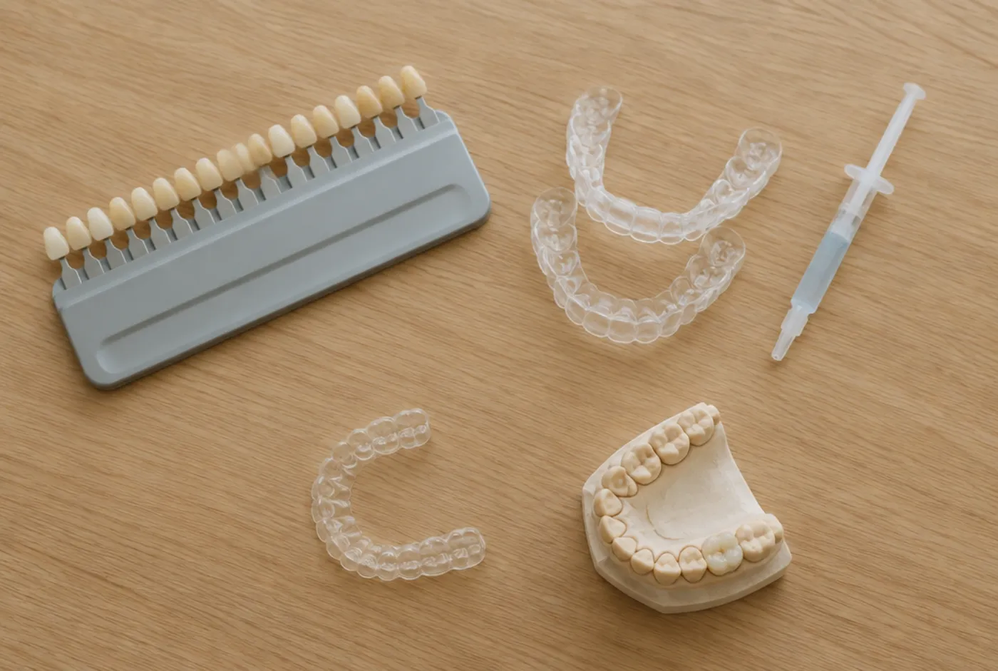 Shade guide, whitening trays, a clear aligner and a porcelain crown on a dental model